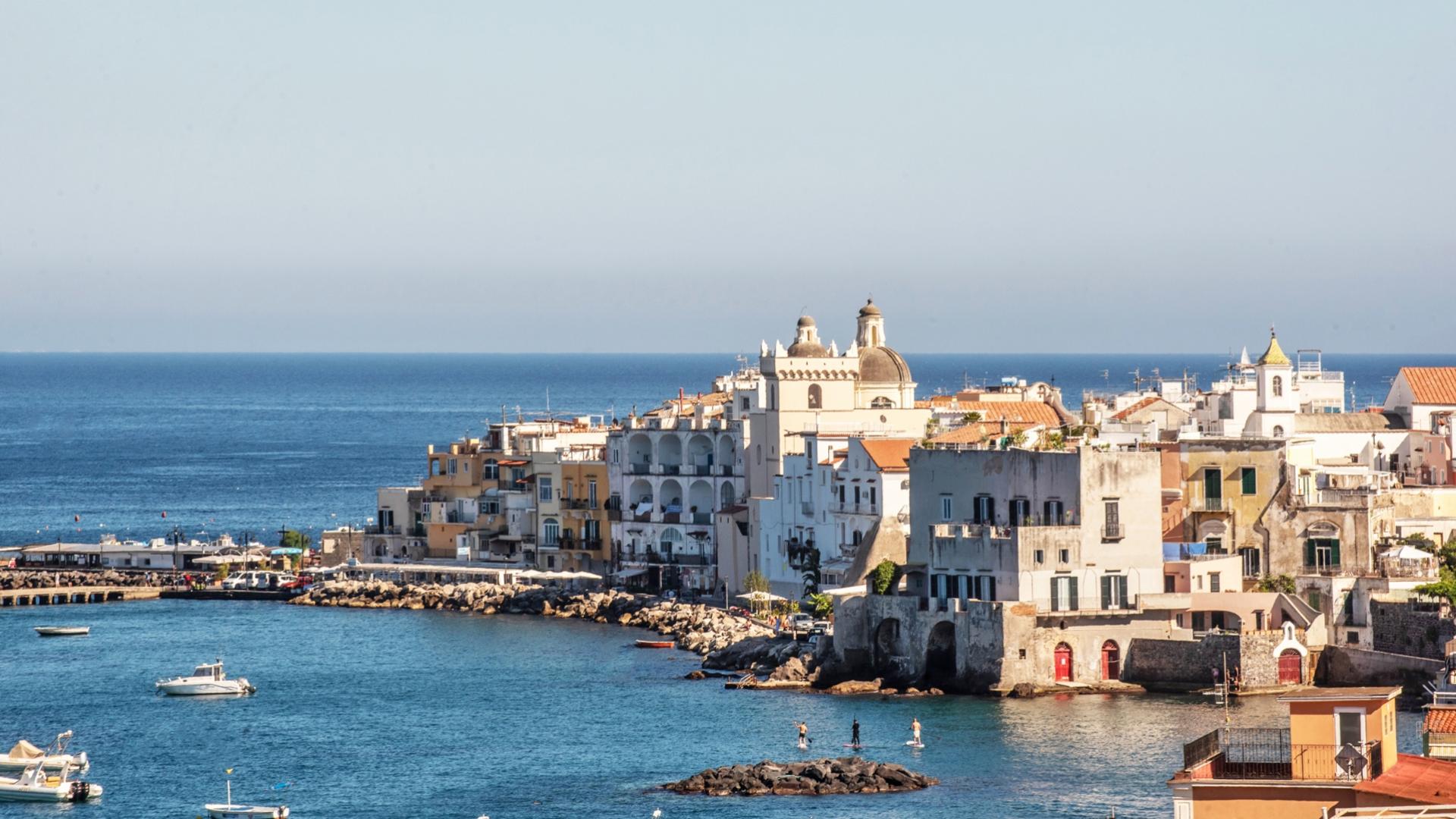 Vista costiera di un pittoresco villaggio marittimo, edifici colorati e mare azzurro brillante.