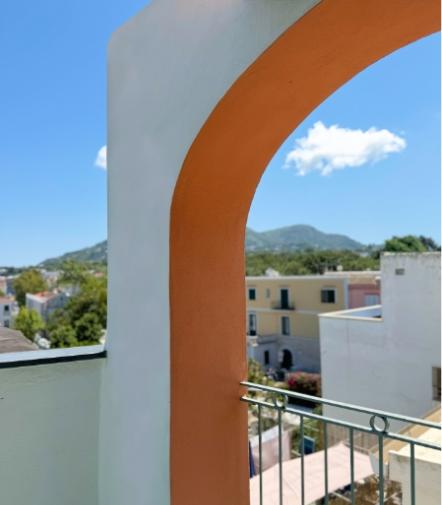 Arco colorato incornicia un paesaggio sereno, cielo azzurro e montagne distanti.