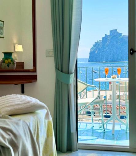 Vista mare da camera, balcone con tavolino, atmosfera rilassante e luminosa.