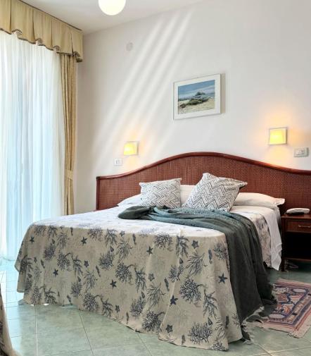 Camera luminosa e accogliente con letto matrimoniale, coperte morbide e decorazioni marine.