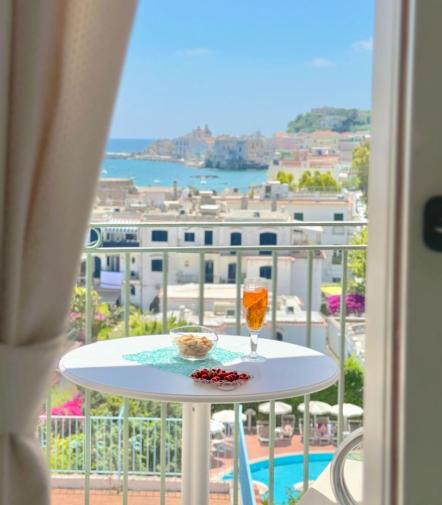 Vista mozzafiato su città costiera, tavolo con drink e snack al sole.