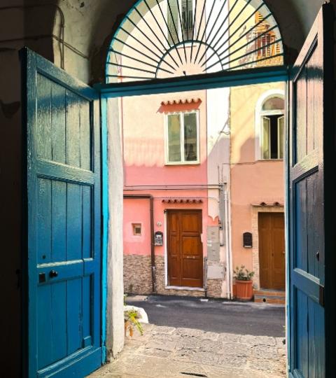 Porta blu aperta su un vicolo colorato, atmosfera calda e accogliente.