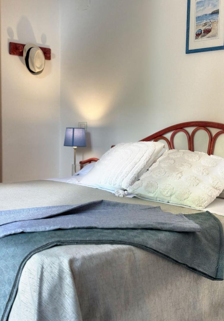 Camera accogliente con letto morbido, lampada blu e quadro marino, atmosfera rilassante.