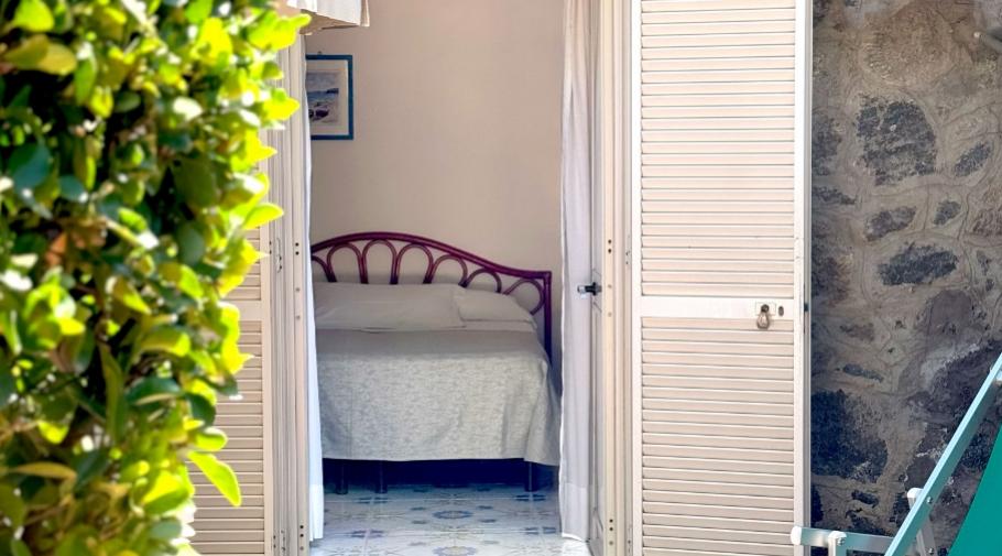 Camera accogliente, luce solare, porte aperte, profumo di mare, relax e tranquillità.