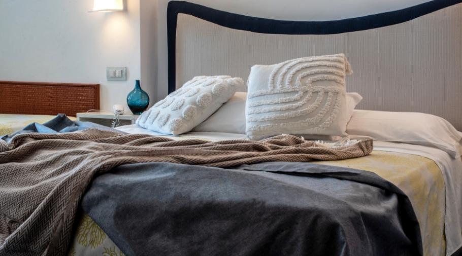 Letto accogliente con coperte morbide e cuscini decorativi, atmosfera rilassante e intima.