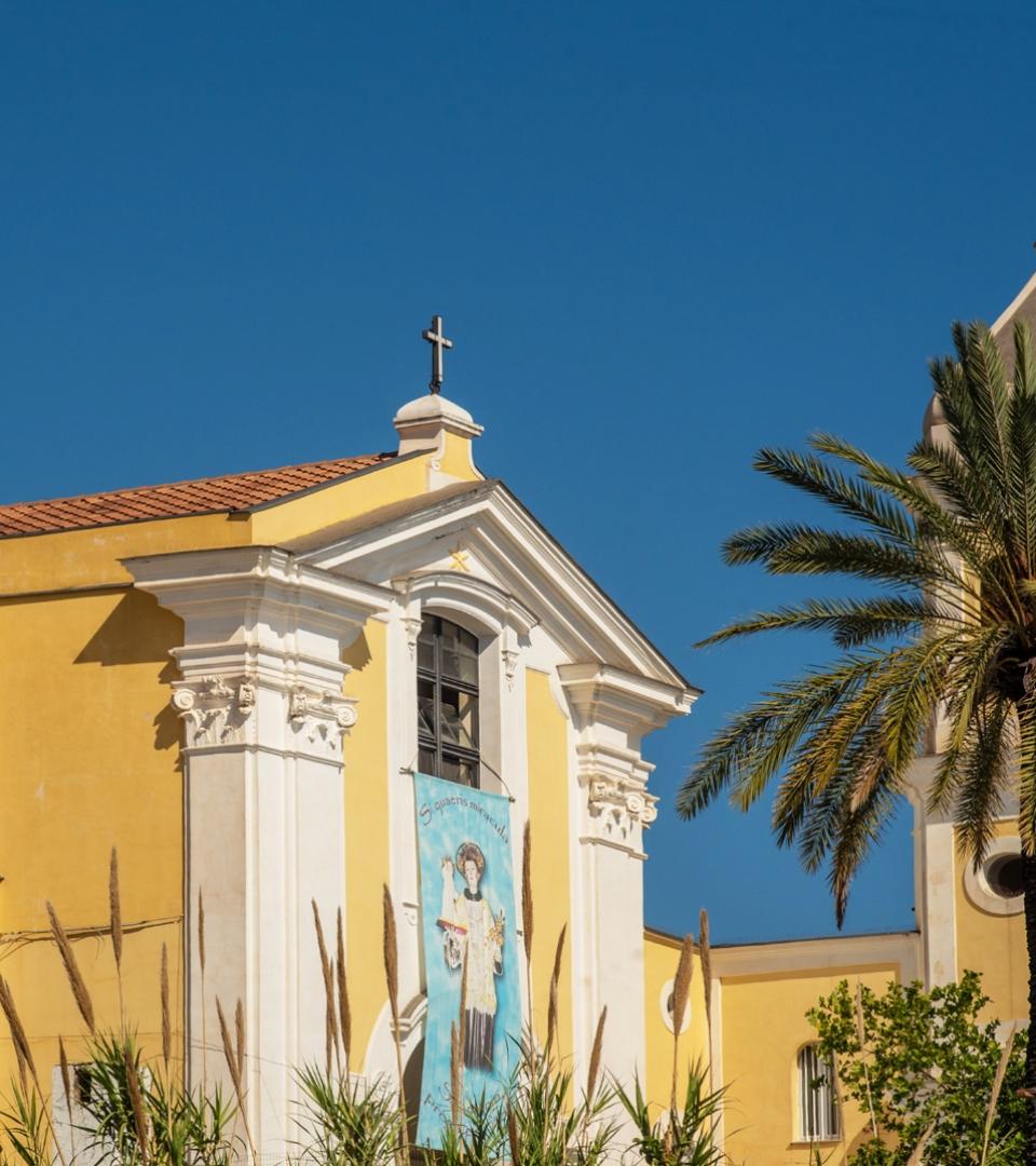Chiesa gialla, cielo blu, palme. Atmosfera serena e luminosa, simbolo di pace e spiritualità.